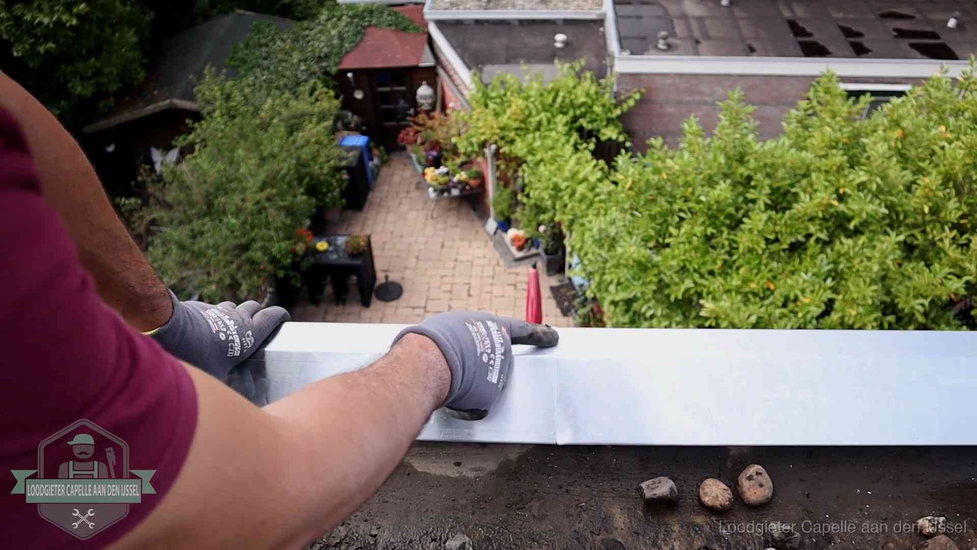 Vakman plaatst een daktrim op de dakrand van een woning in Capelle aan den IJssel