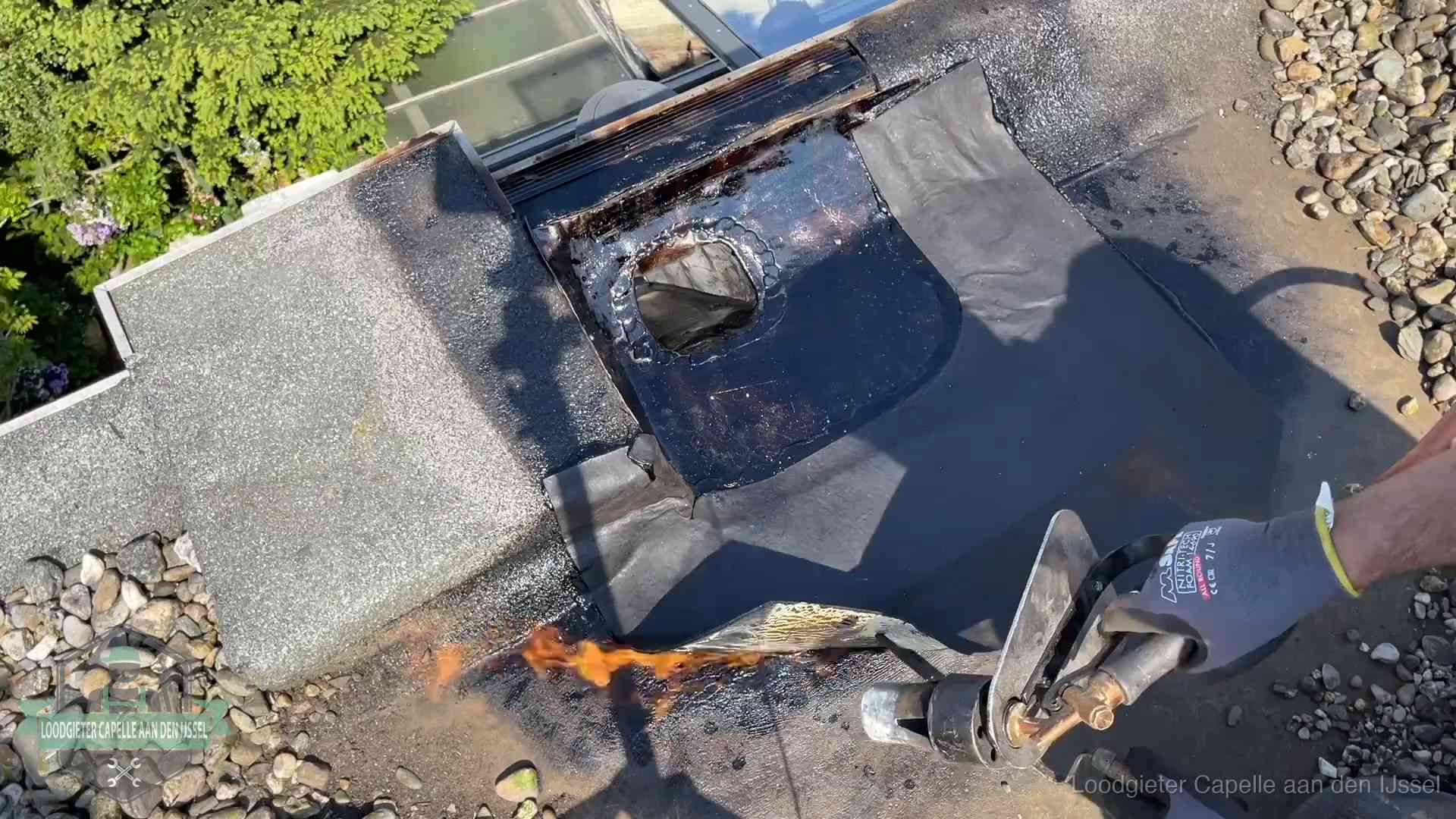 Dakdekker brandt bitumen rond een doorvoer tijdens een daklekkage-reparatie in Capelle aan den IJssel