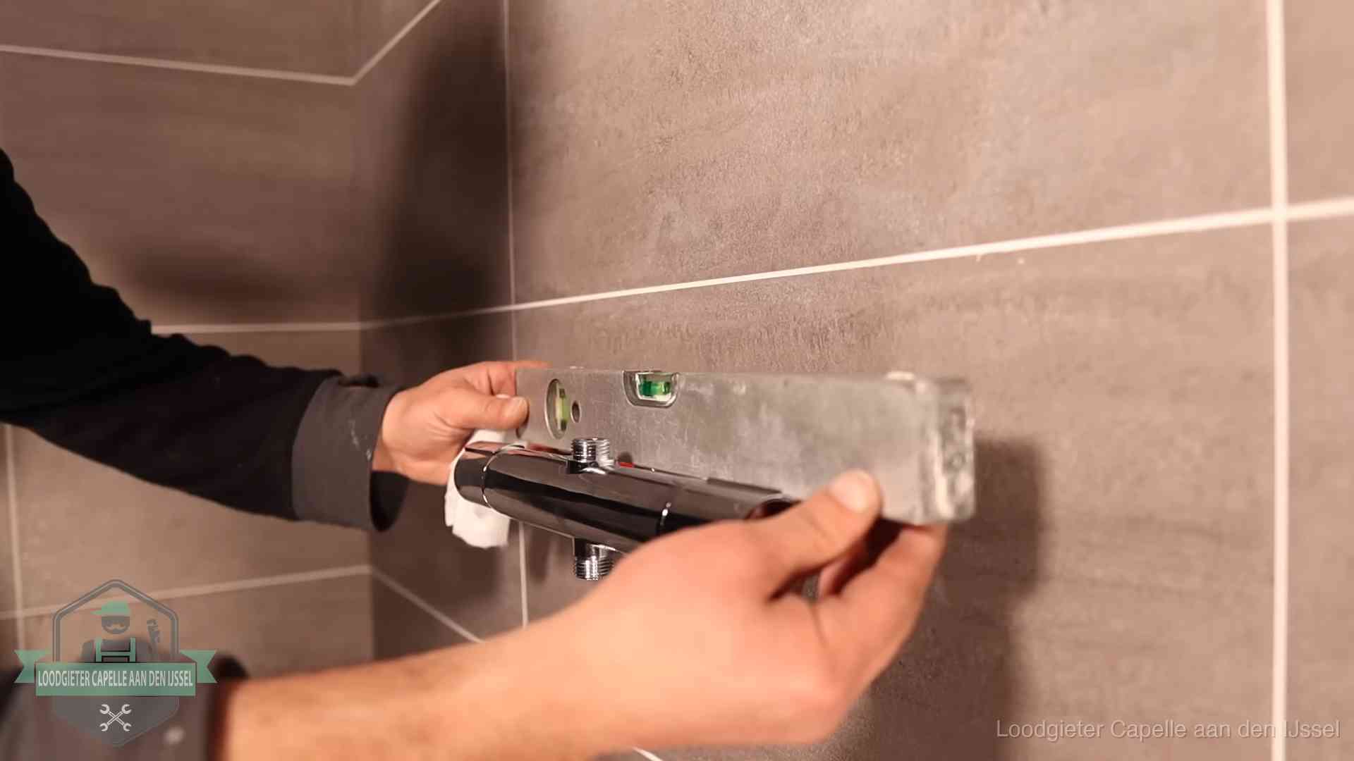 Loodgietersbedrijf voor sanitair in Capelle aan den IJssel Loodgieter lijnt een douchekraan uit met een waterpas in een woning in Capelle aan den IJssel