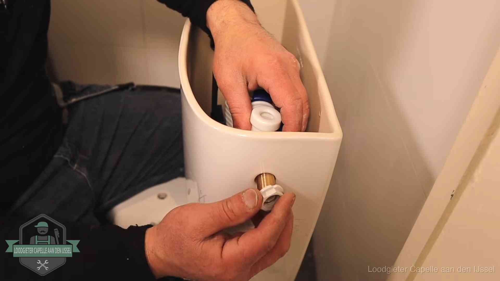 Loodgieter monteert de vlotterkraan van een stortbak bij een toilet in Capelle aan den IJssel
