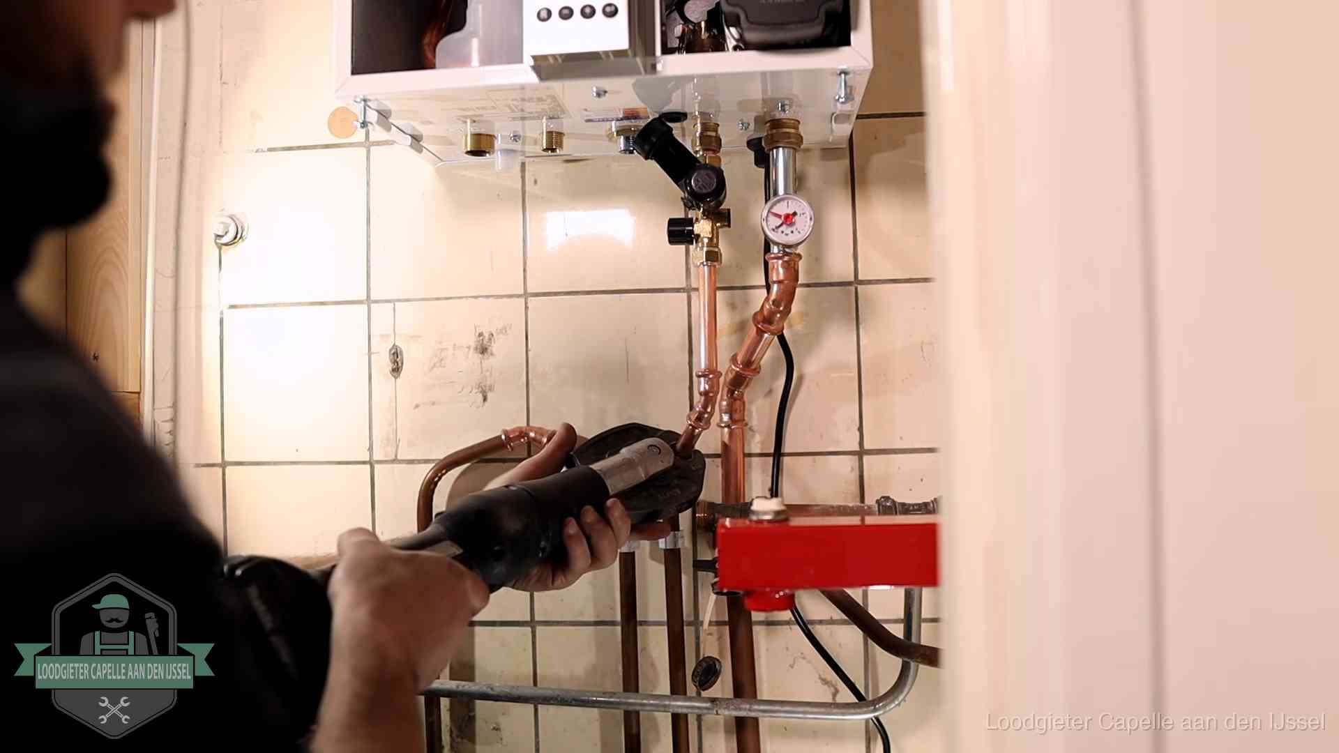 Monteur werkt aan de leidingen onder een cv-ketel in Capelle aan den IJssel