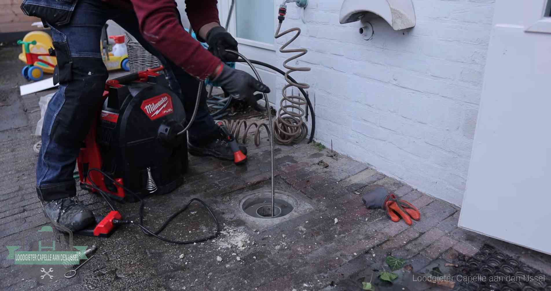 Ontstoppingsputje in de bestrating naast de gevel van een woning in Capelle aan den IJssel