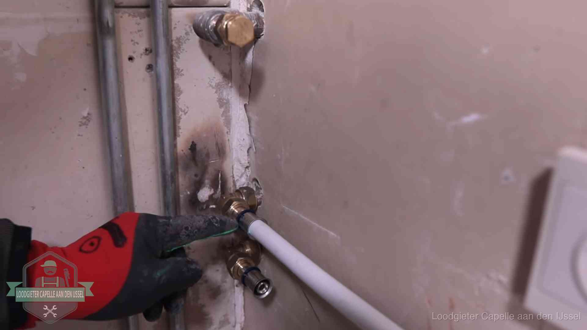 Garantie op loodgieterswerk in Capelle aan den IJssel Loodgieter wijst de persfitting op nieuwe muuraansluitingen aan in een woning in Capelle aan den IJssel