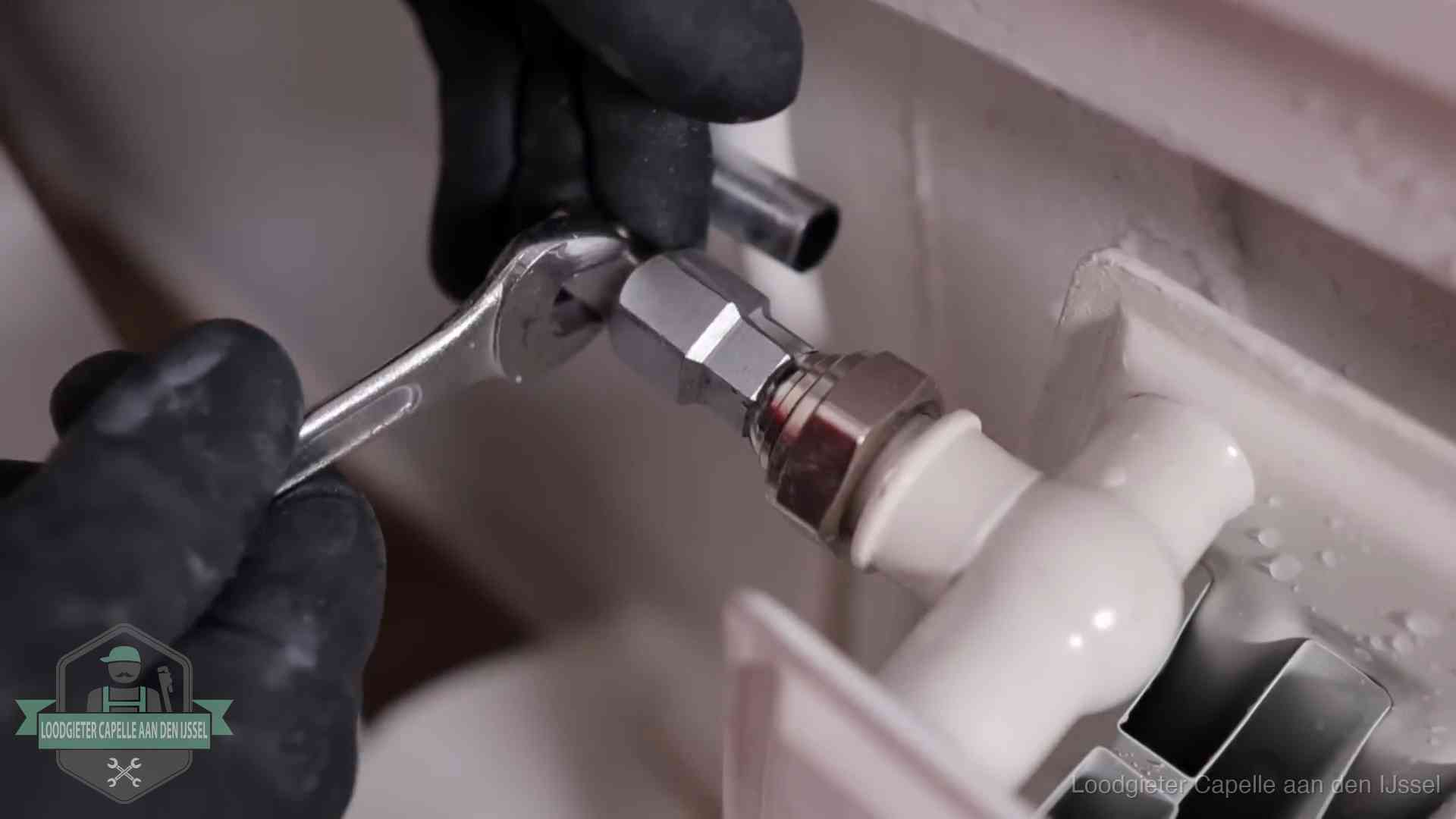 Steeksleutel draait een wartelkoppeling op een radiatorkraan aan in Capelle aan den IJssel