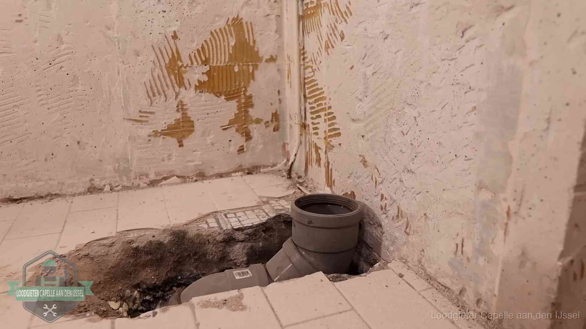 Opengebroken vloer met een nieuwe pvc-rioolbocht in een gegraven sleuf in Capelle aan den IJssel