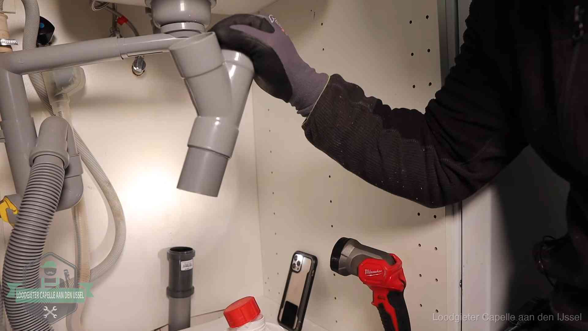 Loodgieter demonteert het sifon- en afvoerwerk onder een gootsteen in Capelle aan den IJssel bij stankklachten