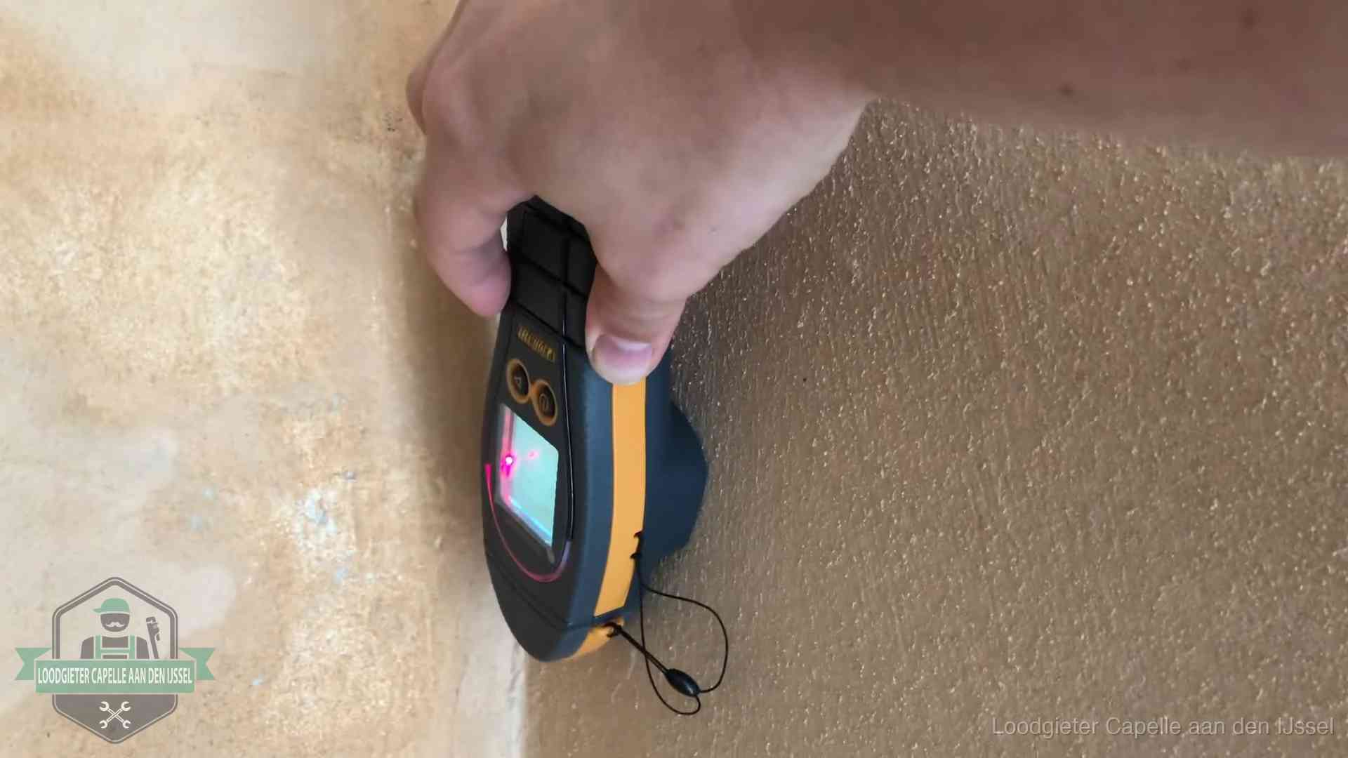 Vochtmeter tegen een muur met vochtplekken tijdens het opsporen van een daklekkage in Capelle aan den IJssel