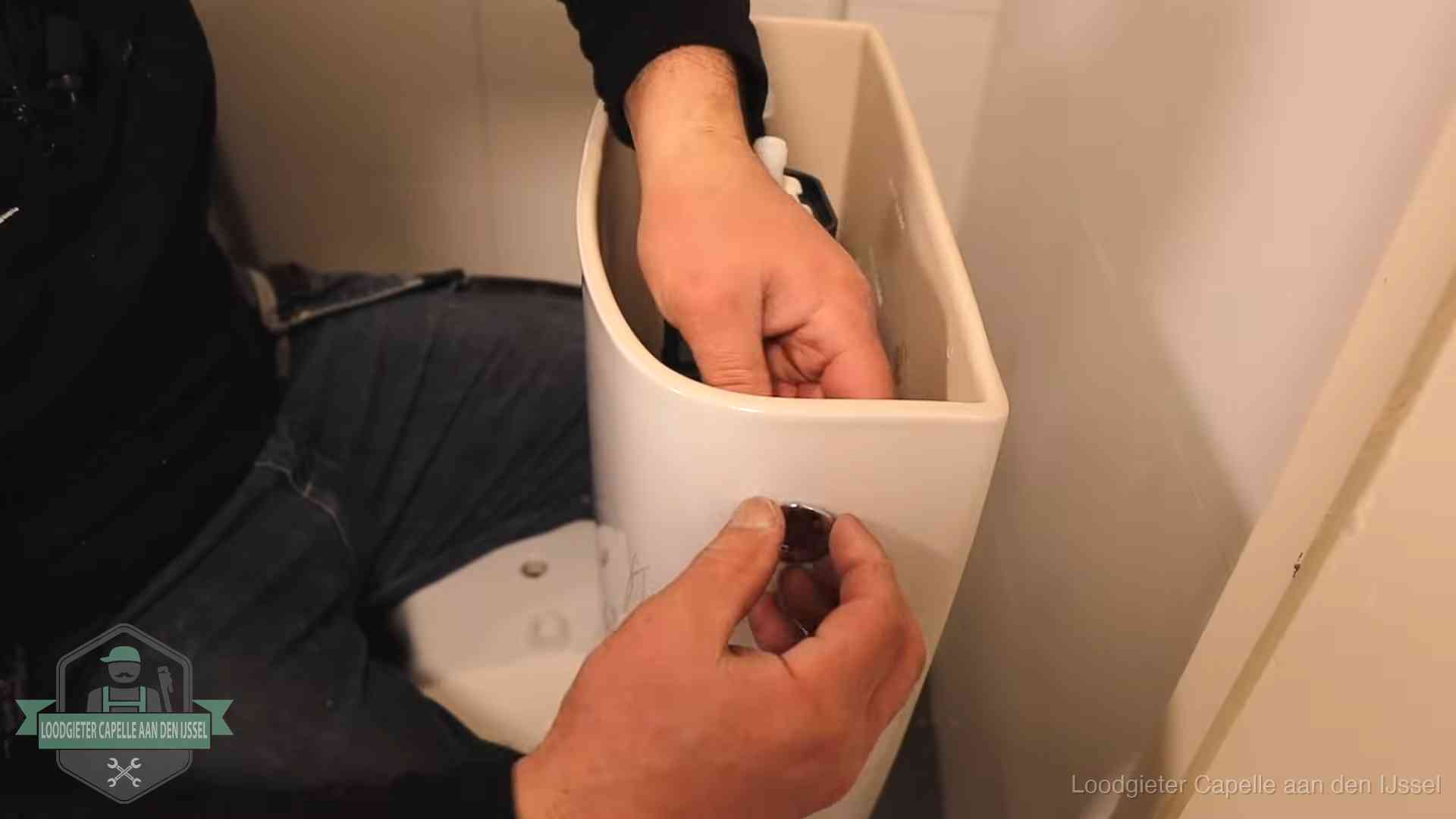 Drukknop van een duoblok-stortbak wordt gemonteerd bij een toilet in Capelle aan den IJssel