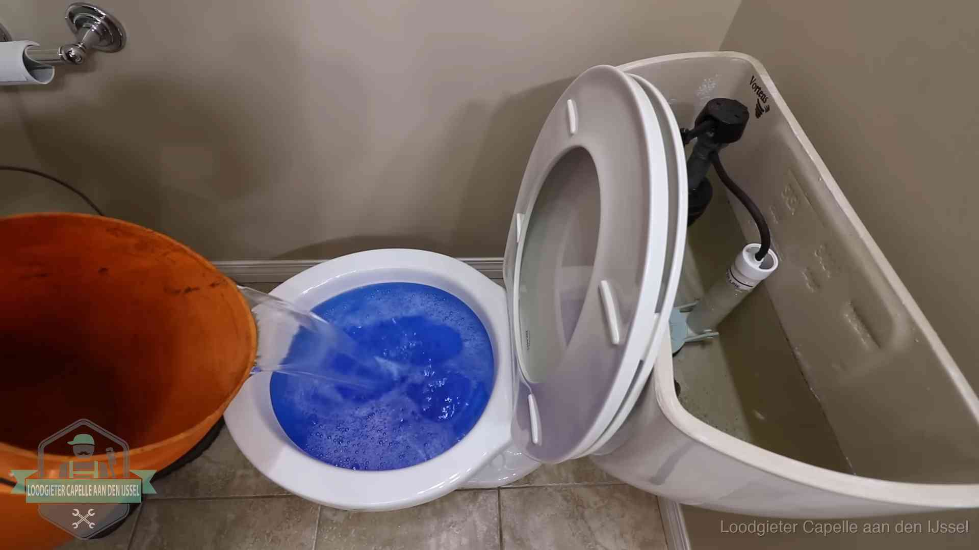 Water bij de wc-pot wordt met een emmer weggewerkt om schade te beperken in Capelle aan den IJssel